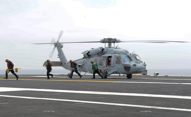 Sailors leaving landing area of an HH-60H Sea Hawk helicopter poster print.