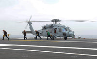Sailors leaving landing area of an HH-60H Sea Hawk helicopter poster print.
