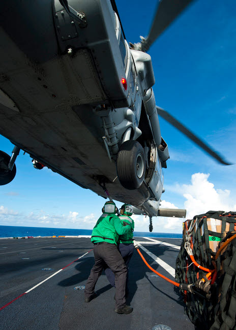 Logistics specialists hooking cargo onto an MH-60S Sea Hawk helicopter poster print.