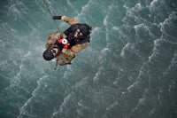 Water rescue training scenario poster print featuring airmen being hoisted out of the water.