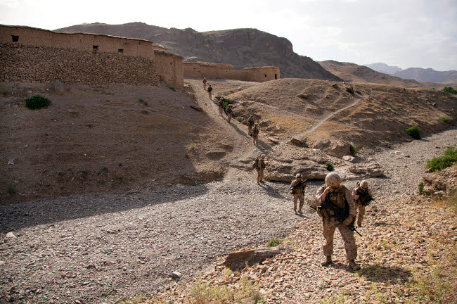 US Marines patrol through a village in Afghanistan poster print, showcasing military dedication and resilience.