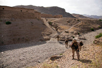 US Marines patrol through a village in Afghanistan poster print, showcasing military dedication and resilience.