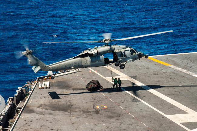 Sailors connecting cargo legs and nets to an MH-60S Sea Hawk military helicopter