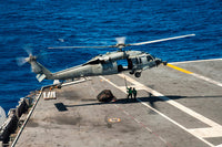 Sailors connecting cargo legs and nets to an MH-60S Sea Hawk military helicopter