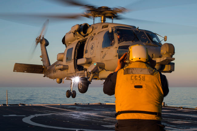 Boatswain's Mate guiding an MH-60R Sea Hawk onto the flight deck poster print.
