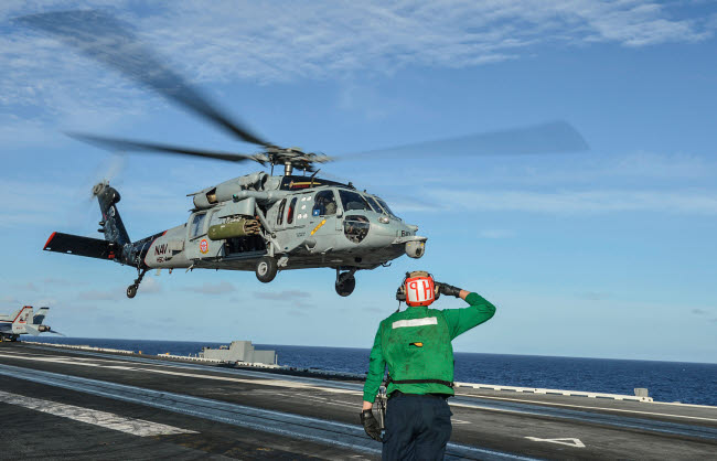 Airman salutes as MH-60S Sea Hawk helicopter departs poster print.