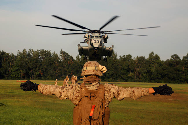 A landing support specialist guiding a CH-53E Super Stallion helicopter poster print.