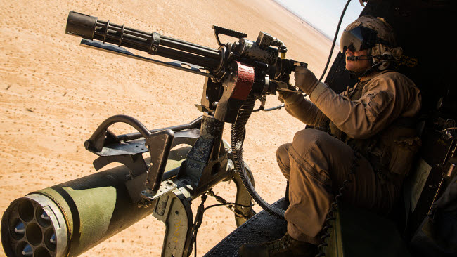A Crew Chief Mounts a M134 Minigun Poster Print showcasing military aviation.