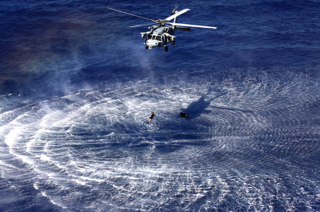MH-60S Seahawk lowers a rescue swimmer into the water poster print