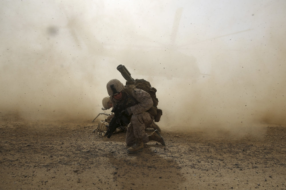 U.S. Marine shielding from dust as CH-53E Super Stallion helicopter lifts off in Afghanistan