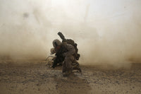 U.S. Marine shielding from dust as CH-53E Super Stallion helicopter lifts off in Afghanistan