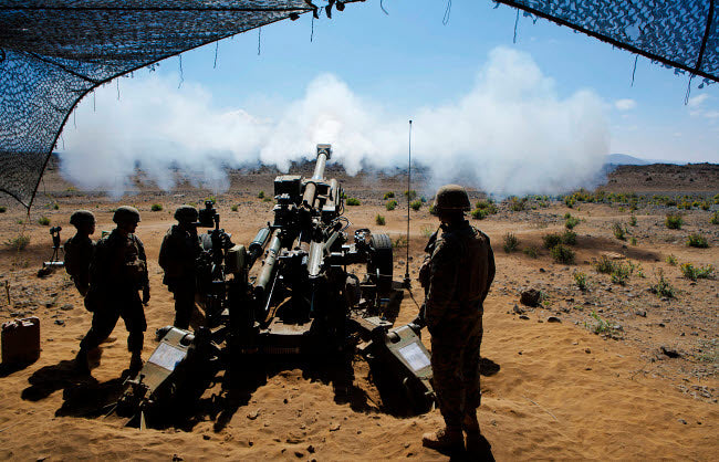 US Marines firing M777A2 Howitzer poster print showcasing military action.