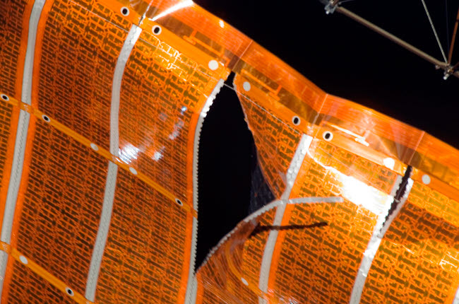 Close-up of a tear in solar array material on the International Space Station poster print.