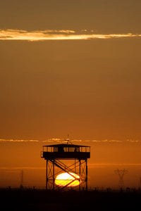 Guard Tower at Sunset Poster Print by Terry Moore showcasing a vibrant sunset sky.