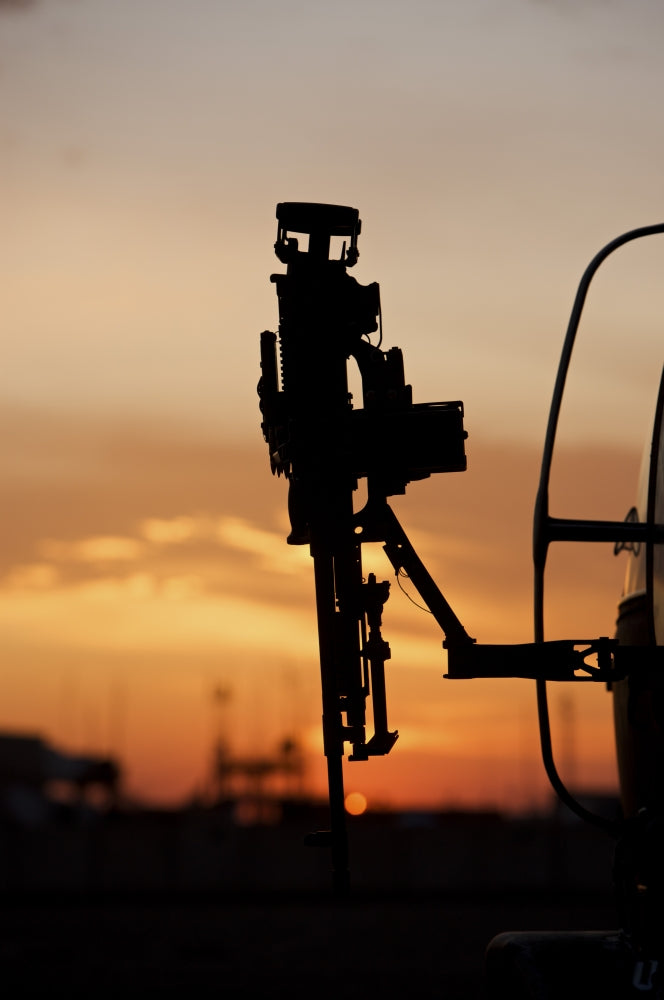 Silhouette of M240G machine gun on UH-60L Black Hawk helicopter at sunset in Baghdad