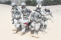Airborne infantry paratroopers carrying injured soldier across desert sand poster print
