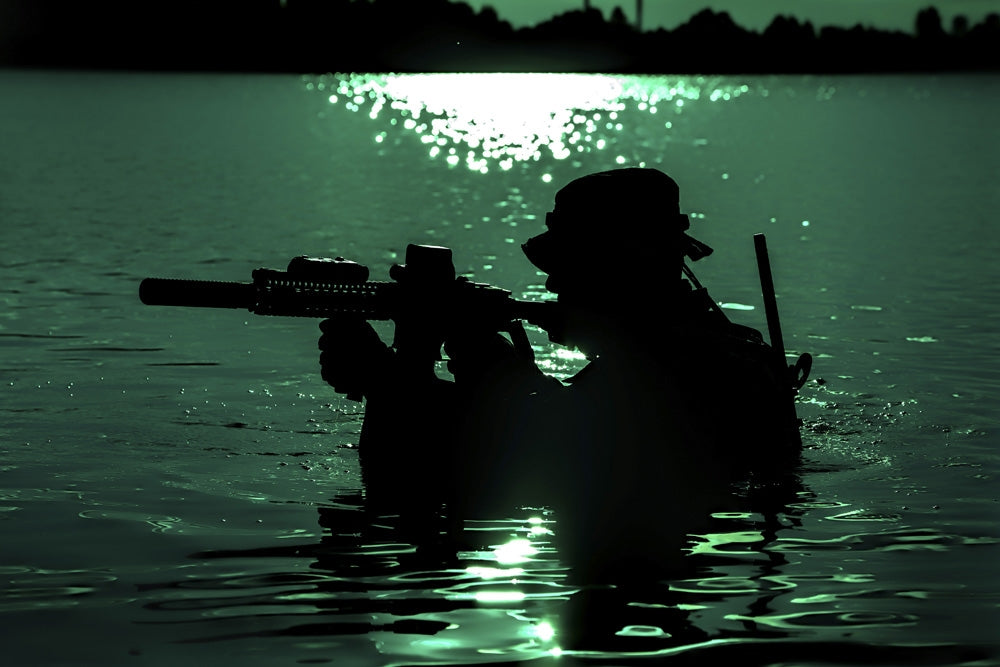 Silhouette of a special forces soldier crossing a river during a night raid in the jungle poster print.