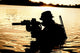 Silhouette of a special forces soldier crossing a river in the jungle poster print