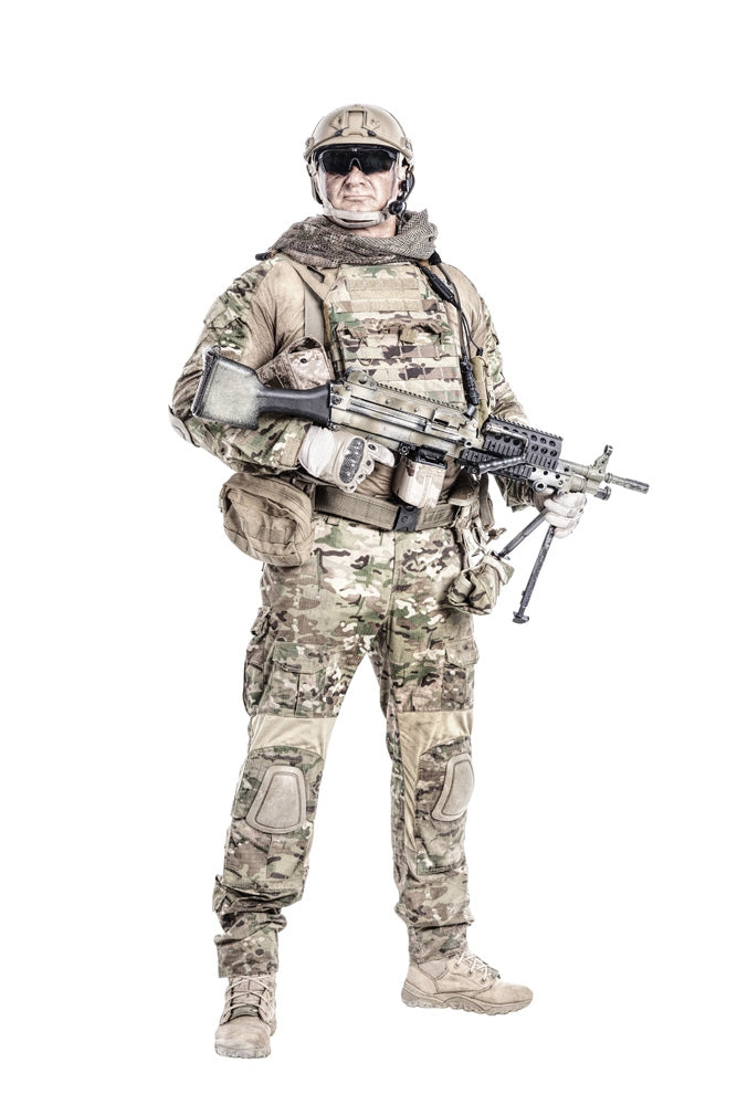 Full-length portrait of muscular soldier in field uniform with machine gun.