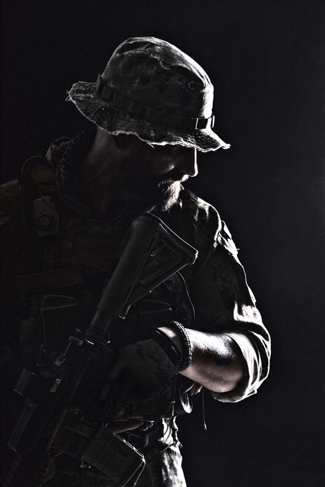 Contour backlight portrait of a bearded special forces soldier in uniform with weapon.