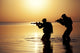 Silhouette of Army soldiers crossing a river at sunset poster print by Oleg Zabielin