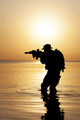 Silhouette of Army soldier with rifle against orange sunset poster print by Oleg Zabielin.
