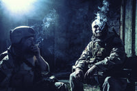 Tired soldiers smoking cigarettes in an abandoned building after battle - Poster Print by Oleg Zabielin.