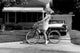 Young woman sitting on bicycle in driveway poster print.