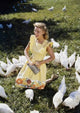 Poster of a teenage girl feeding chickens in a field, high angle view.