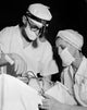 Poster print of a patient receiving treatment from two oral surgeons.
