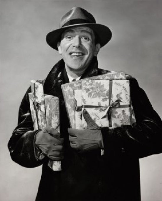 Portrait of a mid adult man smiling while holding Christmas presents.