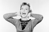 Close-up poster print of a young woman laughing with her hands on her ears.
