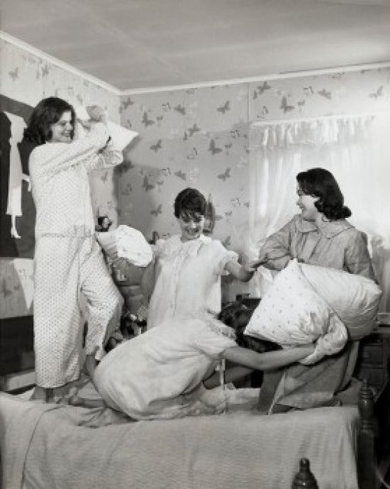 Four teenage girls having a fun pillow fight poster print