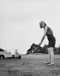 Young woman playing golf on a golf course poster print.