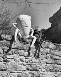 Boy sitting beside a sculpture of Humpty Dumpty poster print