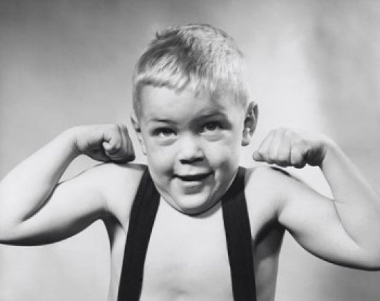 Studio portrait of a boy flexing muscles, inspiring artwork for kids' rooms.