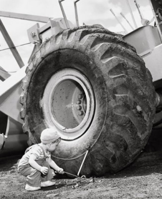 Crouching boy holding a tool next to a bulldozer poster print.