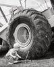 Crouching boy holding a tool next to a bulldozer poster print.