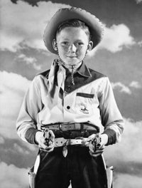 Boy in cowboy costume holding toy guns poster print.