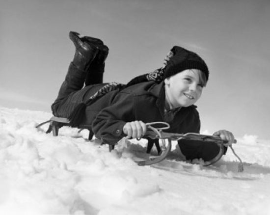 Boy Sliding on a Sled Poster Print showcasing winter fun.