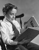 Poster print of a boy sitting in a chair reading a book.