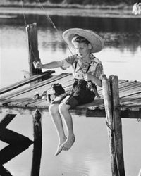 Poster print of a boy fishing on a pier in a tranquil lake.