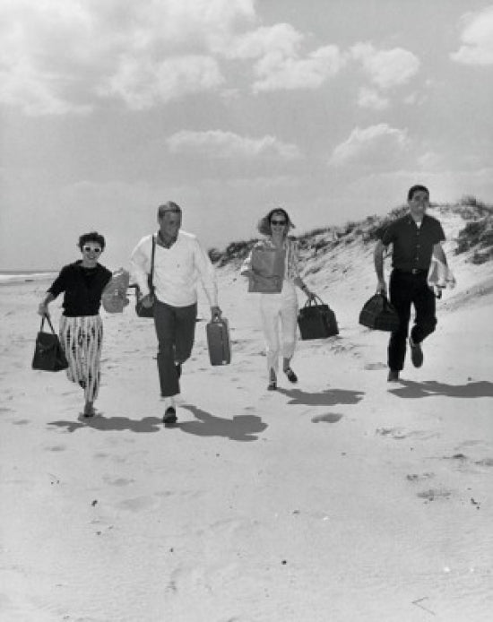 Two mid-adult couples running on the beach poster print.