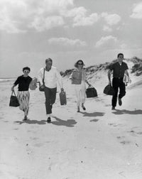 Two mid-adult couples running on the beach poster print.