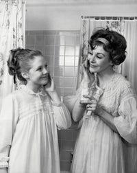 Mother and daughter applying moisturizer on their cheeks poster print.