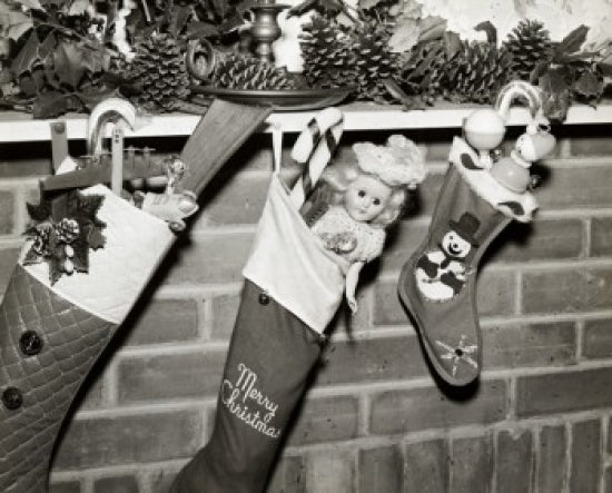 Close-up of three Christmas stockings filled with toys hanging from a mantelpiece
