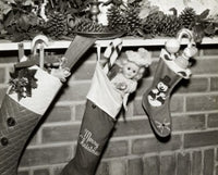 Close-up of three Christmas stockings filled with toys hanging from a mantelpiece