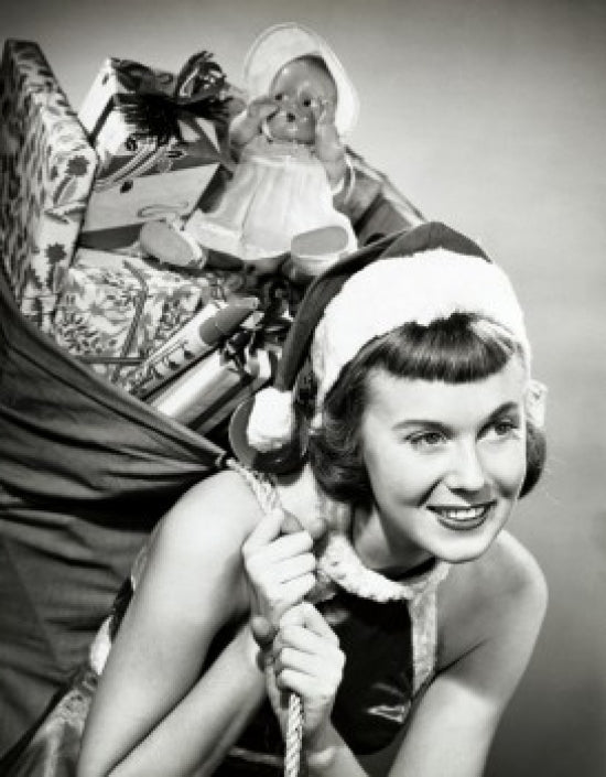 Close-up of a young woman joyfully carrying a sack of Christmas presents.
