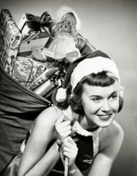 Close-up of a young woman joyfully carrying a sack of Christmas presents.