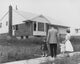 Family Togetherness Poster Print featuring a mid-adult couple with two children in front of a house.